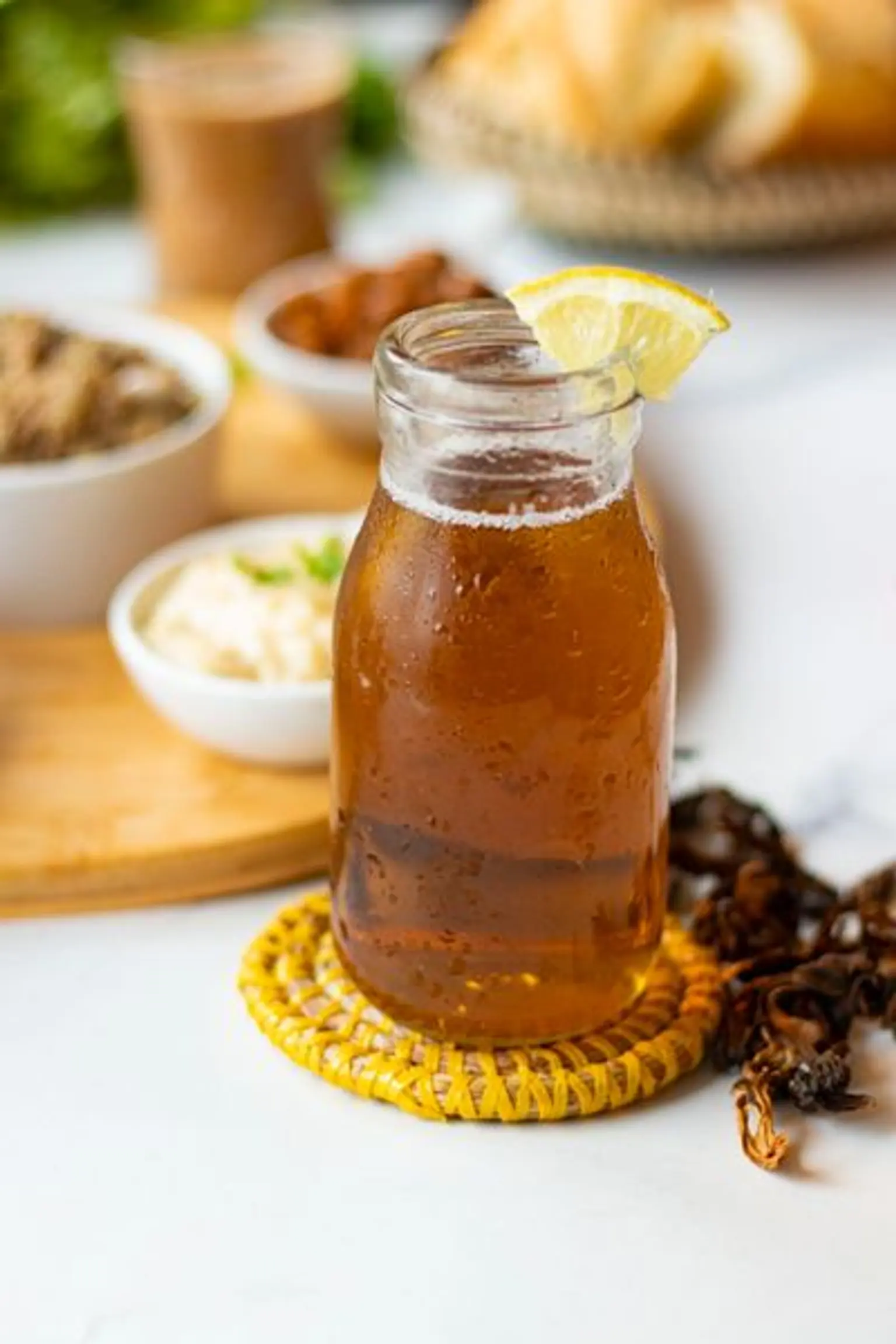 petite bouteille en verre de jus de bissap blanc avec un morceau de citron