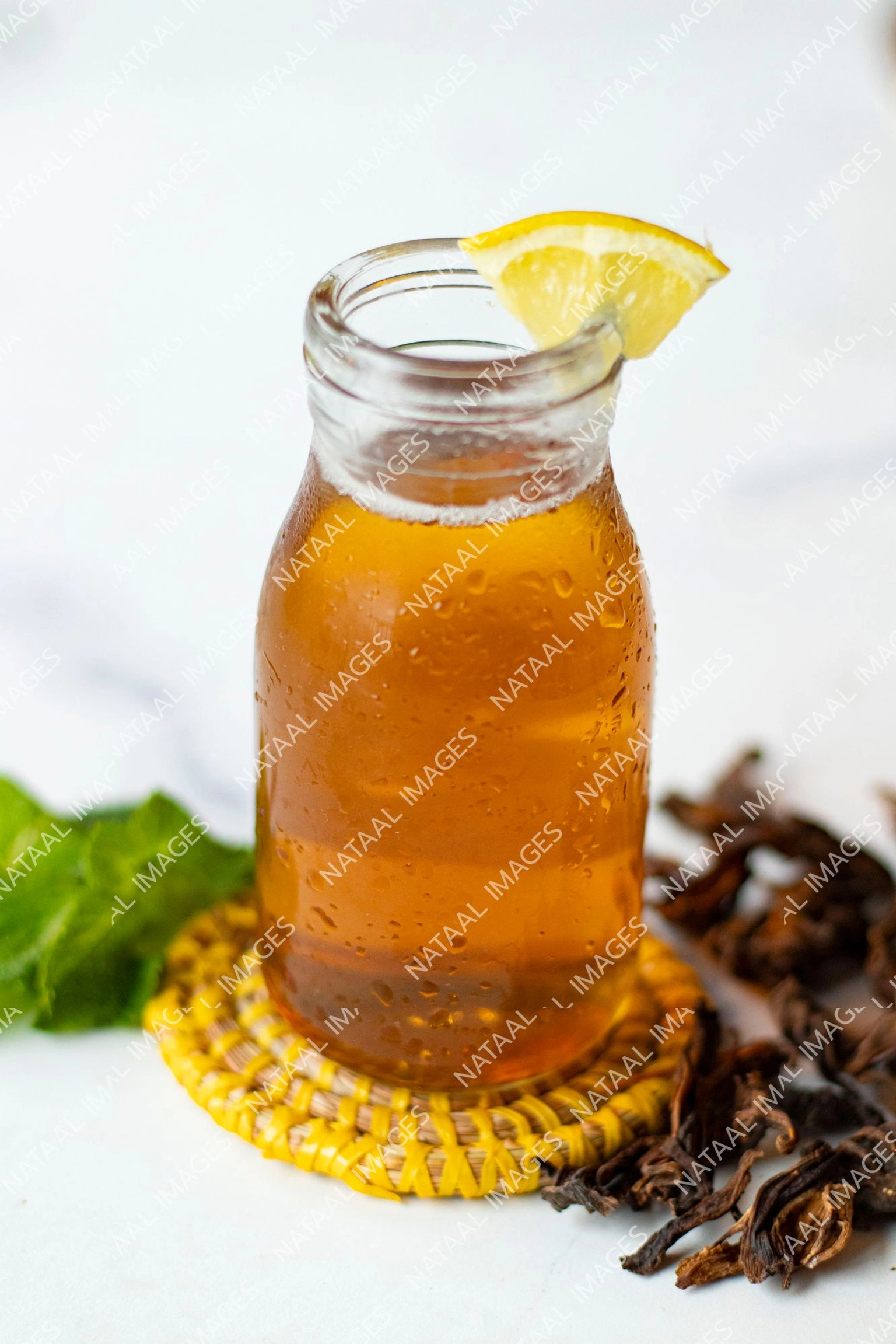 zoom petite bouteille en verre de jus de bissap blanc avec un morceau de citron