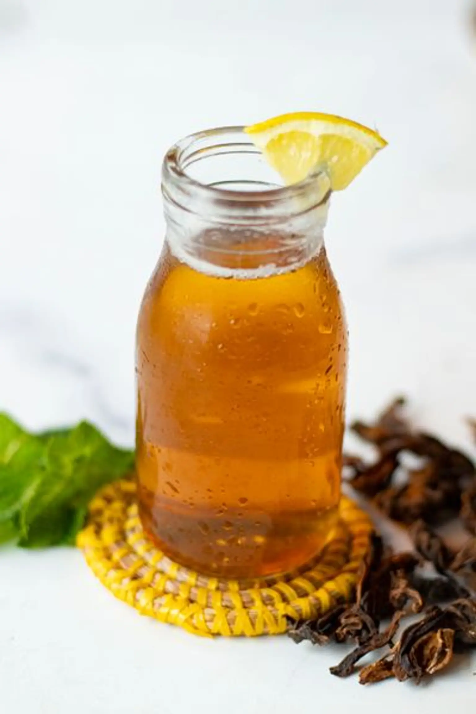 zoom petite bouteille en verre de jus de bissap blanc avec un morceau de citron