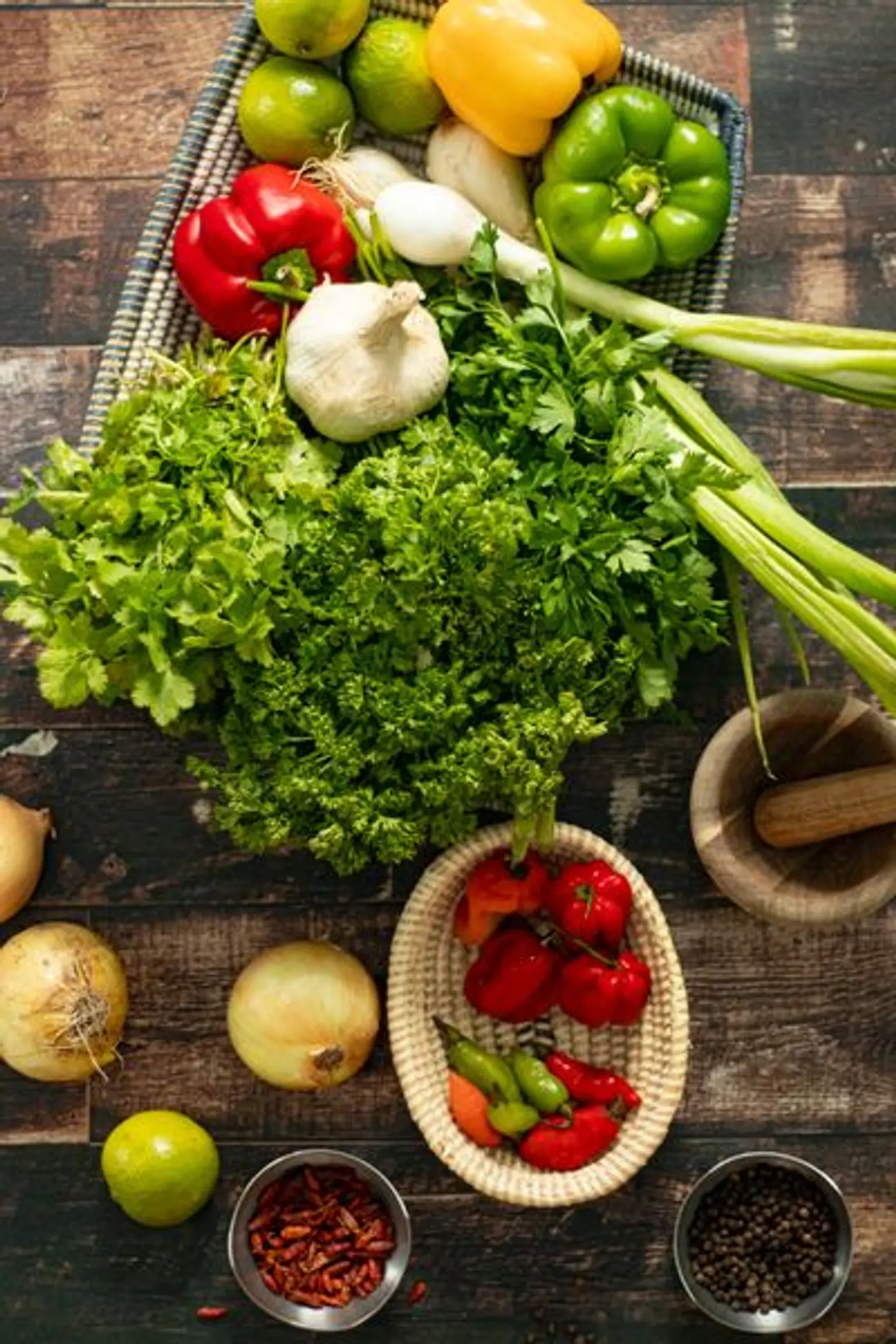 panier de legumes et panier de piments sur une plan de travail en bois avec a cote des oignons